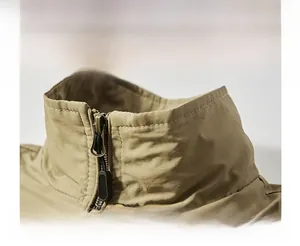 Detail of khaki outdoor vest showing windproof stand collar and metallic zipper texture