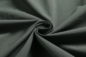 Macro shot of dark olive green outdoor jacket fabric showing fine woven texture and matte finish