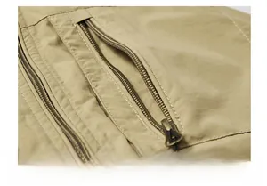 Detail of khaki outdoor vest showing dual metallic zippers and durable woven fabric