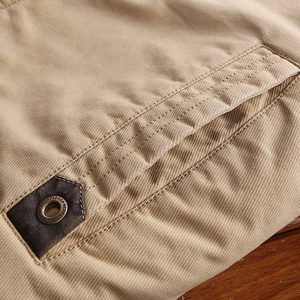 Detail of khaki twill jacket pocket with leather patch and outdoor fashion engraving
