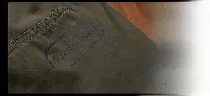 Detail of olive green jacket fabric with double stitching and FASHION lettering print