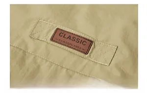 Close-up of brown leather patch with Classic 1902 text on outdoor khaki vest