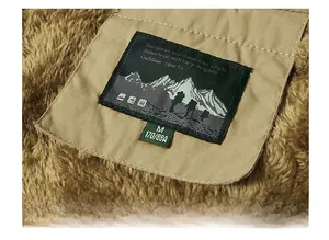 Close-up of the black woven neck label and soft khaki fleece texture on the winter vest