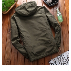 Flat lay of an olive green men's hooded jacket on a rustic wood background with vintage props
