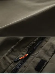 Close-up of military green outdoor jacket fabric with zipper and orange pull cord