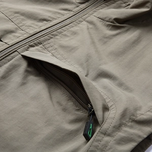 Detailed close-up of khaki outdoor vest showing zipper pocket and fine stitching quality
