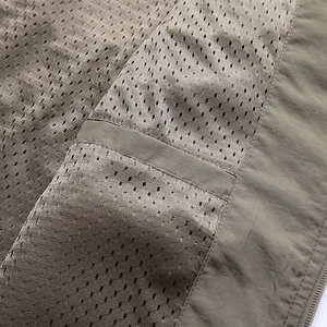 Macro view of olive green outdoor vest featuring breathable mesh lining and neat stitching