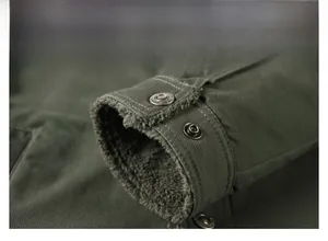 Macro detail of dark green jacket cuff with thick fleece lining and vintage metal button