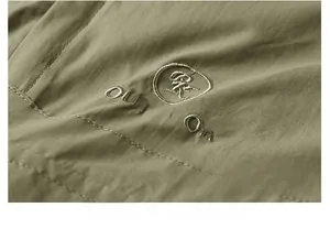 Close-up of circular outdoor embroidery on olive green vest with detailed fabric texture