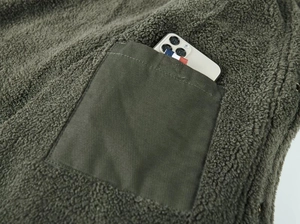 Detailed macro view of the olive green fleece jacket with functional canvas patch pocket