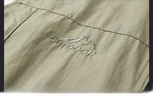 Detail of army green outdoor vest showing high-quality embroidery with mountain logo