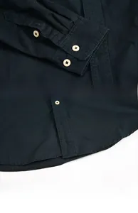 Detail view of dark blue cotton shirt cuff buttons, stitching and curved hem design