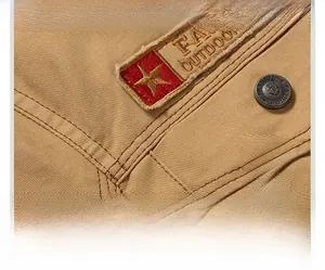 Close-up of khaki outdoor jacket detailing heavy canvas seams and star emblem patch
