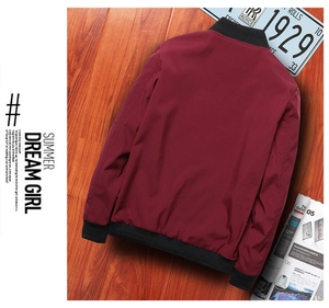 Rear view of wine red bomber jacket with black ribbed cuffs on vintage wood background