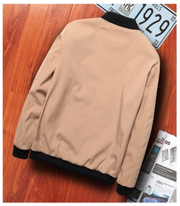 Macro view of khaki bomber jacket sleeve with functional zipper pocket and black rib cuff