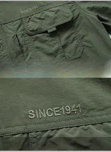 Close-up of SINCE 1941 embroidery and multi-pocket design on army green outdoor shirt
