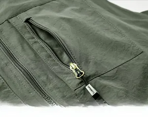 Detail of metal zippers on olive green multi-pocket outdoor vest with sports puller