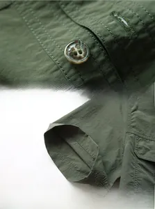 Detail of army green outdoor shirt showing engraved buttons and reinforced stitching
