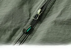 Detailed close-up of a durable zipper with a sports puller on a green outdoor fishing vest