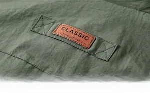 Detail of classic brown leather patch on the back of green outdoor utility vest