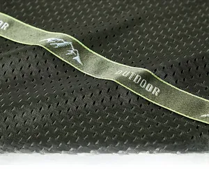Detail of army green mesh fabric with embroidered outdoor logo and precision stitching