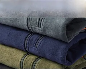 Close-up of stacked fleece jackets in grey, navy, and green showing thick thermal fabric