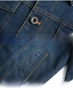 Detail of dark blue denim jacket showing metal buttons and pocket with orange stitching