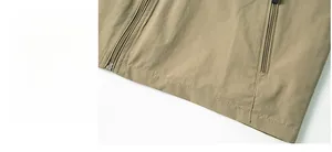 Detail of multi-pocket khaki vest hem with durable metal zippers and high-quality stitching
