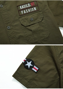 Detail of military style short sleeve shirt with embroidered chest patches and shoulder badge