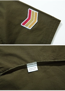Detail of military green shirt showing V-shaped stripe embroidery and 95% cotton fabric label