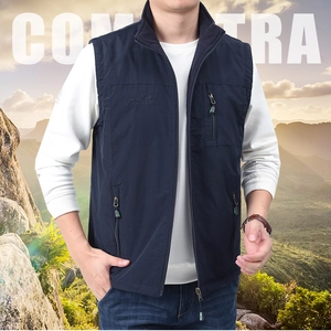 Detail of navy blue outdoor vest featuring standing collar and zip pocket against mountain