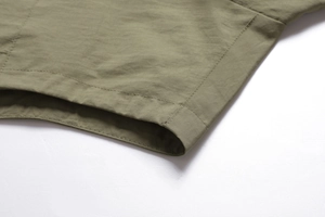 Detail of army green outdoor vest showing reinforced double-stitch hem and cotton fabric