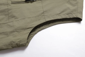 Macro detail of military green outdoor vest featuring reinforced zipper and fabric texture
