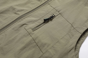 Close-up of military green outdoor vest featuring durable metal zippers and textured fabric