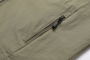 Close-up of olive green outdoor vest featuring a zipper pocket and SPORTS puller detail