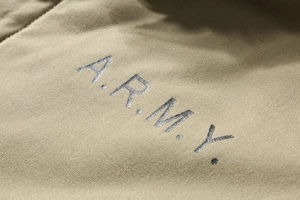 Macro view of army green canvas jacket fabric with grey A.R.M.Y. printed letters