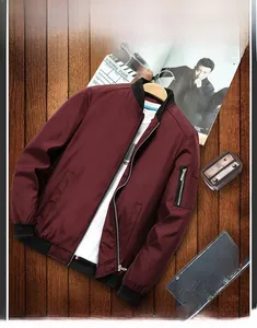 Detail of burgundy bomber jacket featuring a utility sleeve pocket and ribbed black cuffs