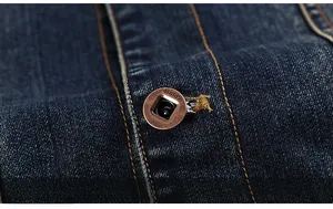 Detail of dark blue denim jacket placket with vintage copper buttons and orange stitching