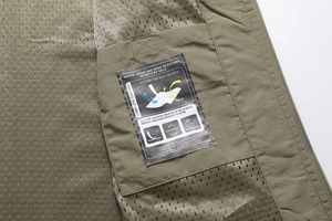 Detail view of military green vest with breathable mesh lining and waterproof tech label