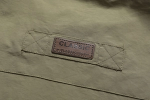Detailed close-up of brown leather classic label on olive green outdoor vest fabric