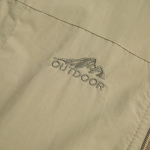 Close-up of khaki outdoor vest featuring mountain embroidery and durable textured fabric