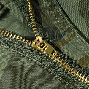 Close-up of brass zipper on men's camouflage cargo shorts made of cotton fabric
