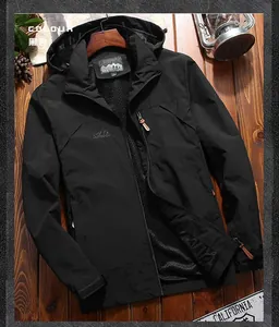 Detail of black outdoor hooded jacket with white chest logo on a vintage wooden background