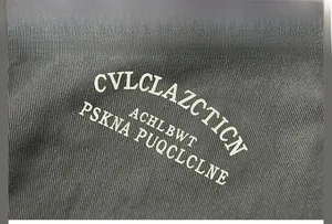 Détail de lettres blanches imprimées sur une veste en coton gris montrant le procédé d'impression