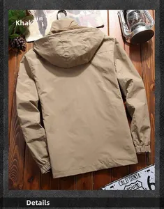 Rear view of khaki hooded tactical jacket on a rustic wooden surface with autumn leaves
