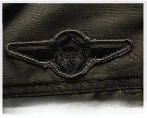 Close-up of military-style embroidered wing patch on olive green flight jacket fabric
