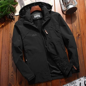 Men's black hooded outdoor jacket with windproof fabric on a rustic wooden background