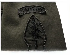 Detail of military green tactical jacket featuring embroidered airborne army patches