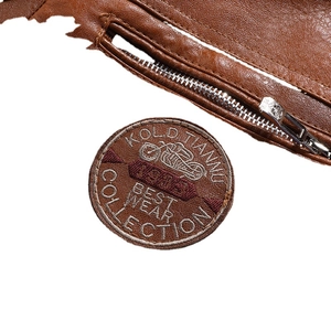 Close-up of vintage brown leather jacket with motorcycle embroidery and metal zipper detail