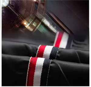 Detail of black jacket fabric featuring signature red, white, and blue striped ribbon trim